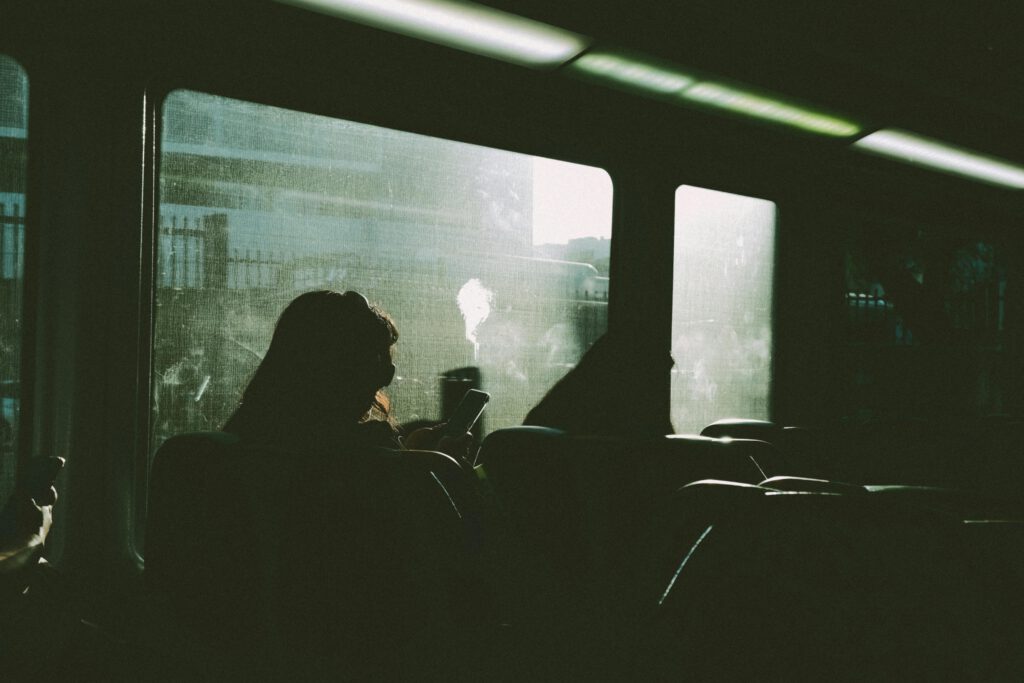 pexels-photo-30626449-30626449 Silhouette of a person using a phone on a train journey, sunlight streaming in.