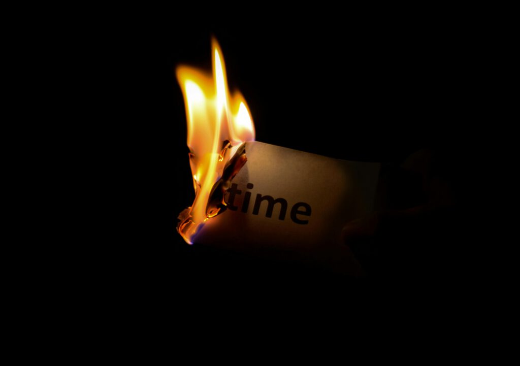 pexels-photo-33930 A close-up of a paper with the word 'time' burning against a dark background.